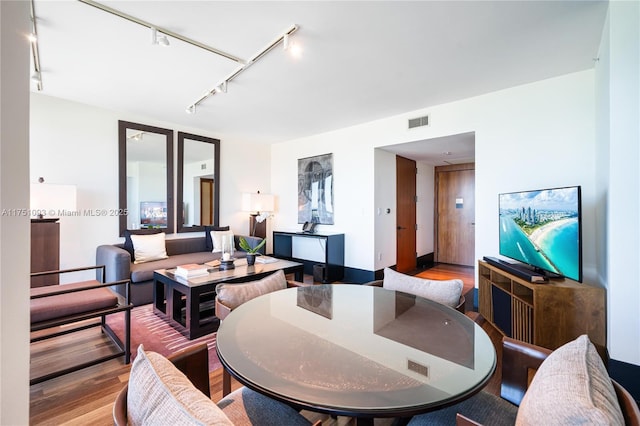 living area featuring visible vents and wood finished floors