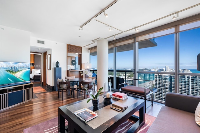 living area featuring a city view, wood finished floors, visible vents, expansive windows, and track lighting