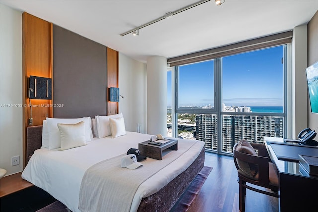 bedroom featuring expansive windows, track lighting, and dark wood-style flooring