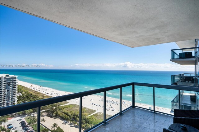 balcony featuring a water view and a beach view