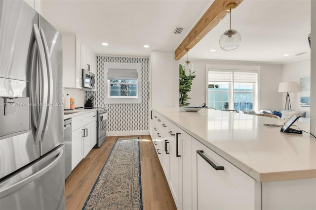 kitchen featuring visible vents, light wood-style floors, appliances with stainless steel finishes, beam ceiling, and wallpapered walls