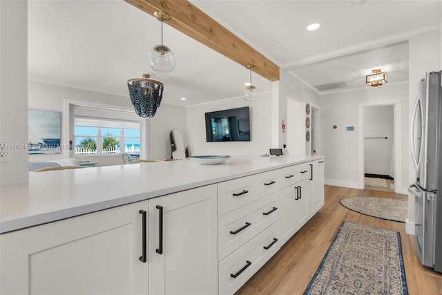 kitchen featuring white cabinets, beamed ceiling, decorative light fixtures, freestanding refrigerator, and light countertops