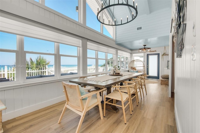 sunroom with a chandelier, a view of the beach, a water view, and visible vents