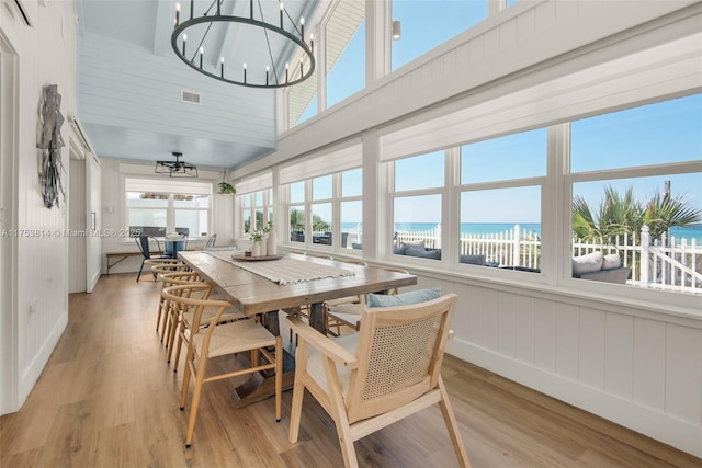 sunroom / solarium featuring a water view, a view of the beach, visible vents, and an inviting chandelier