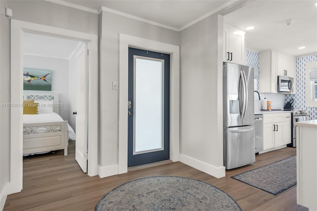 interior space featuring appliances with stainless steel finishes, wood finished floors, and white cabinetry