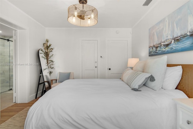 bedroom featuring crown molding, visible vents, ensuite bathroom, a ceiling fan, and wood finished floors