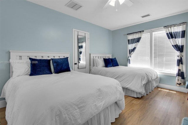 bedroom with wood finished floors, visible vents, and a ceiling fan