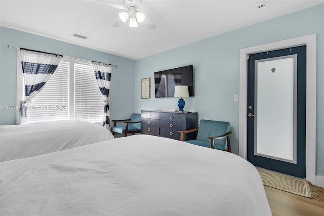 bedroom with ceiling fan, visible vents, and wood finished floors