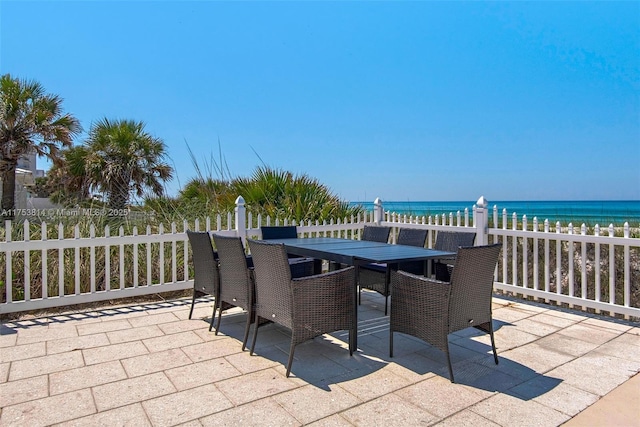 view of patio with a beach view, outdoor dining area, and a water view