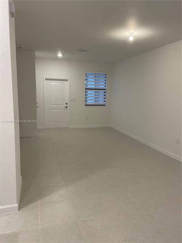 empty room featuring visible vents, baseboards, and a textured ceiling