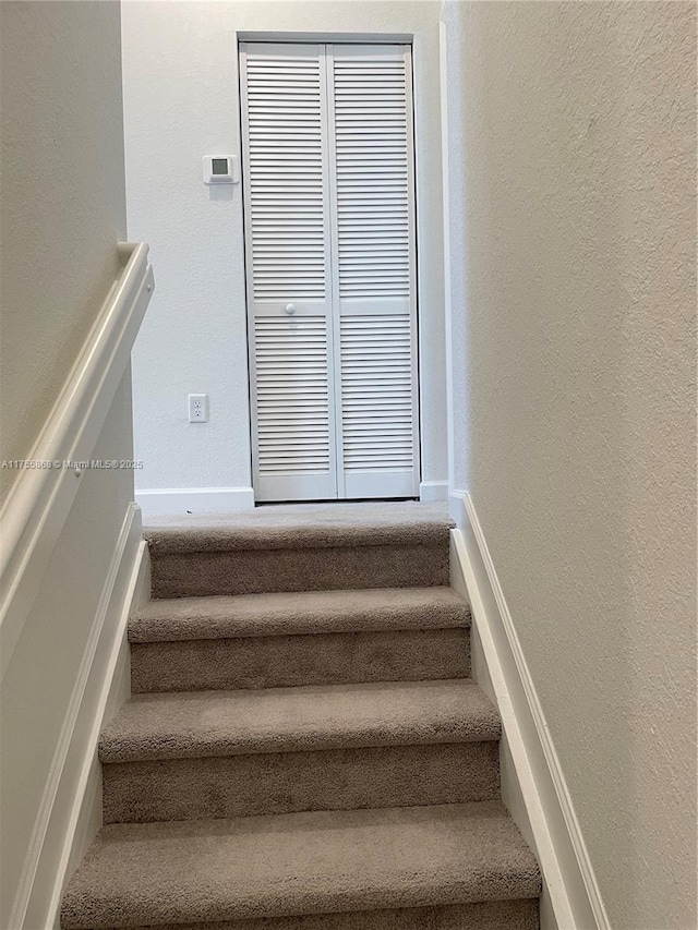 stairs with a textured wall and baseboards