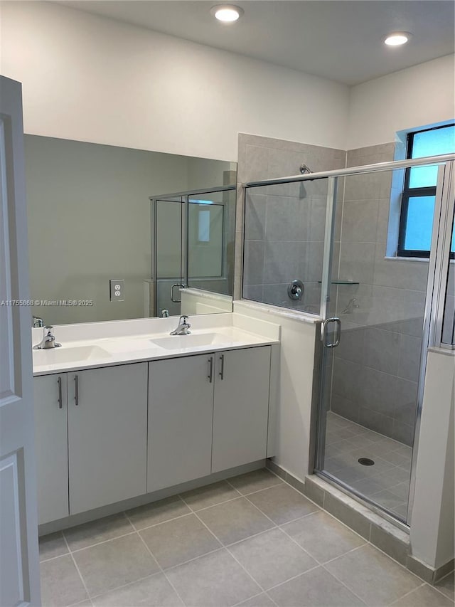 bathroom with double vanity, a stall shower, a sink, and tile patterned floors