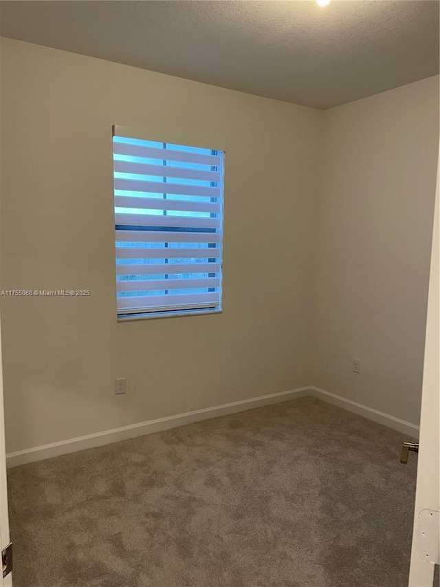 carpeted empty room featuring a textured ceiling and baseboards