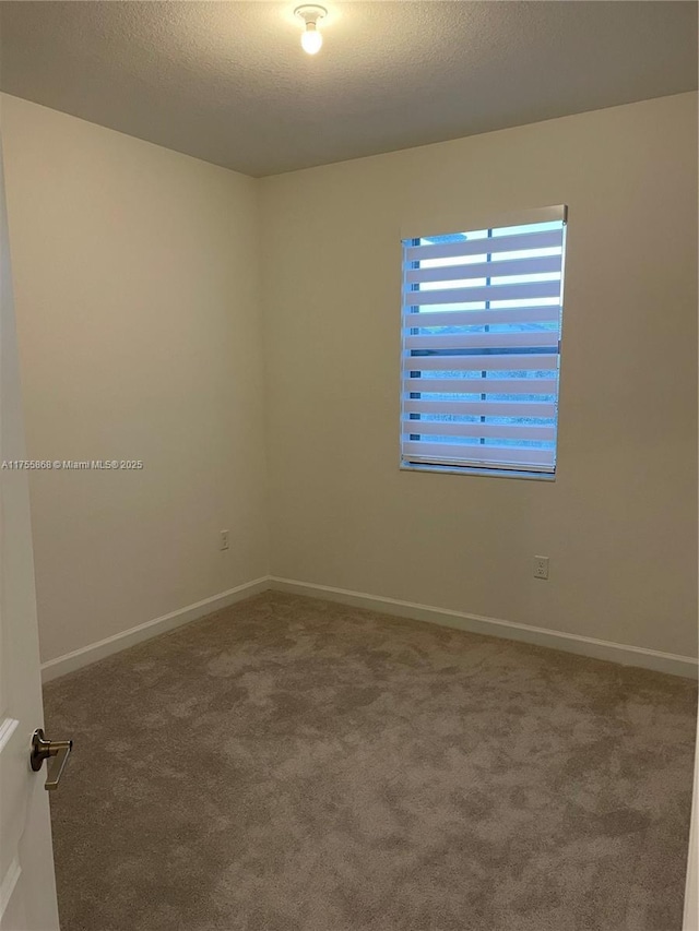 carpeted empty room featuring a textured ceiling and baseboards