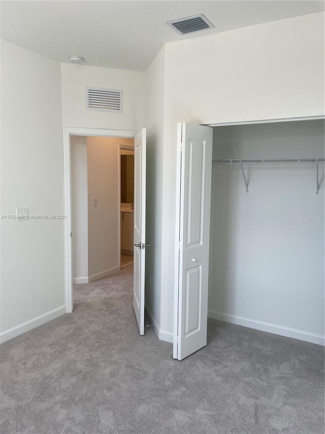 unfurnished bedroom featuring carpet floors, a closet, visible vents, and baseboards