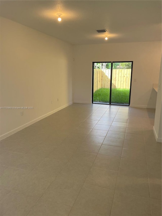 tiled empty room with visible vents and baseboards