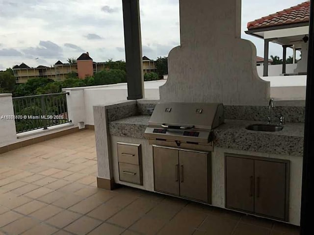 view of patio with exterior kitchen, a sink, and grilling area