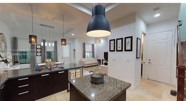 kitchen with hanging light fixtures, dark stone counters, a sink, and recessed lighting