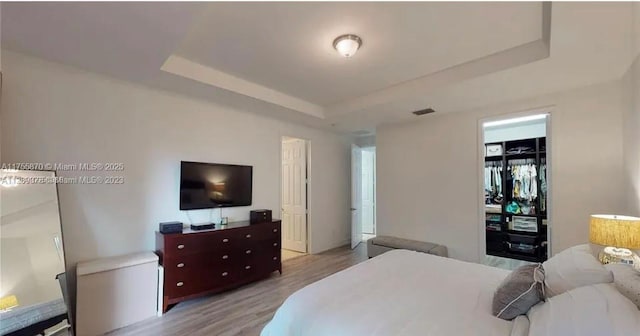 bedroom featuring wood finished floors, a closet, a raised ceiling, and visible vents