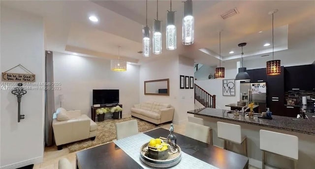 dining area featuring stairs, a raised ceiling, and recessed lighting