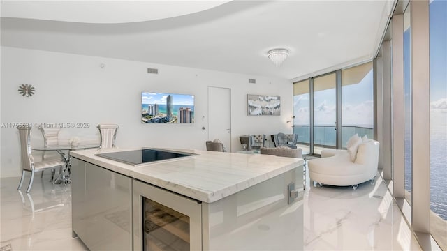18975 Collins Ave Unit 3504, Sunny Isles Beach, FL 33160 - kitchen with light marble finish flooring, black electric stovetop, a kitchen island, expansive windows, and wine cooler