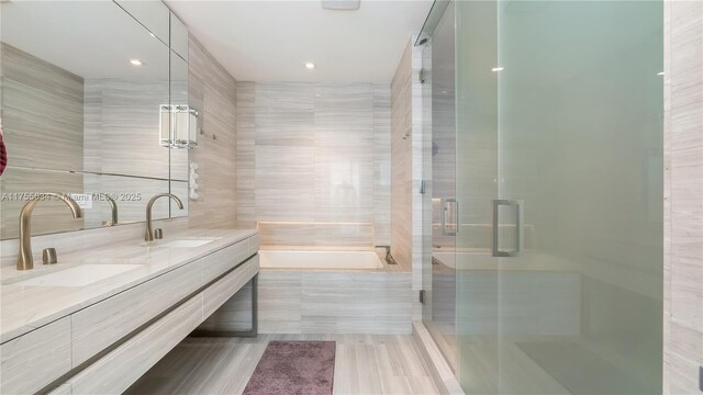 18975 Collins Ave Unit 3504, Sunny Isles Beach, FL 33160 - bathroom with double vanity, a garden tub, a shower stall, tile walls, and recessed lighting
