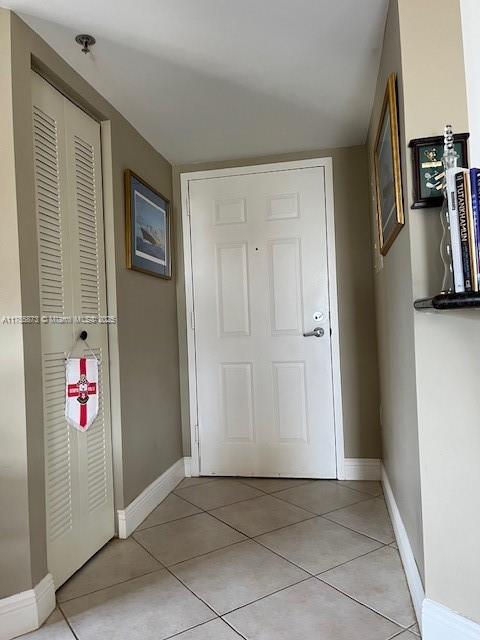 doorway to outside featuring light tile patterned floors and baseboards