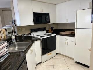 kitchen featuring dark countertops, freestanding refrigerator, a sink, range with electric cooktop, and black microwave