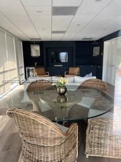 dining area with a drop ceiling and wood finished floors