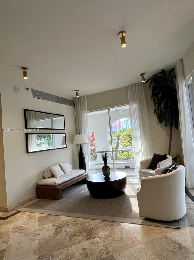 2351 Douglas Rd Unit 1109, Miami, FL 33145 - sitting room featuring a healthy amount of sunlight, stone finish floor, and baseboards