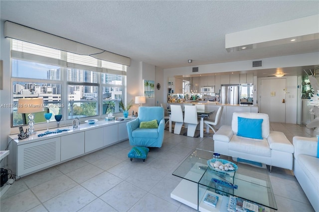 living area featuring light tile patterned floors, a textured ceiling, and visible vents