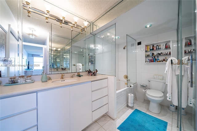 full bath featuring toilet, tile patterned flooring, a textured ceiling, vanity, and tile walls