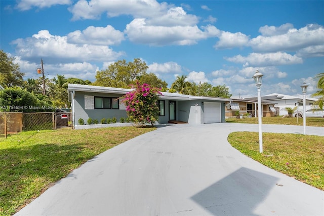 view of front of property featuring a garage, concrete driveway, a front lawn, and fence