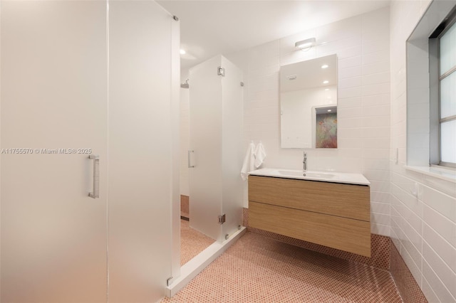 bathroom featuring a stall shower, tile patterned flooring, tile walls, and vanity