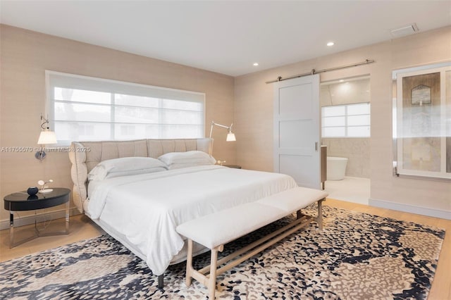 bedroom with baseboards, a barn door, wood finished floors, and recessed lighting