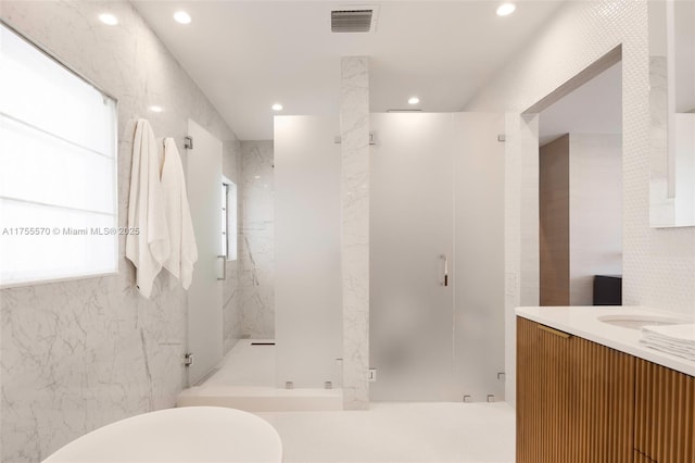 full bath with visible vents, recessed lighting, a marble finish shower, tile walls, and vanity