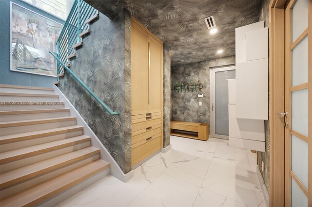 stairway featuring visible vents and marble finish floor