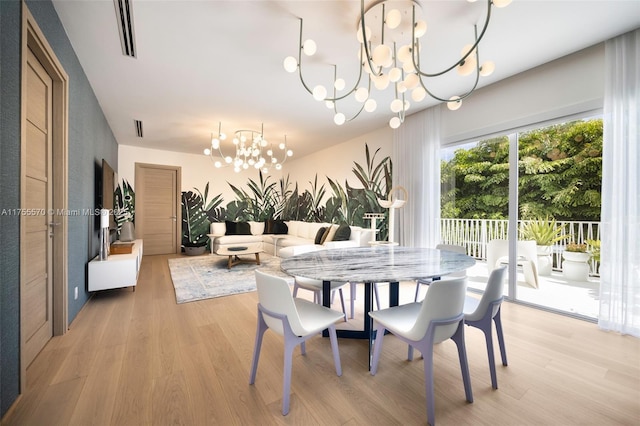 dining area featuring light wood-style flooring, visible vents, and a chandelier