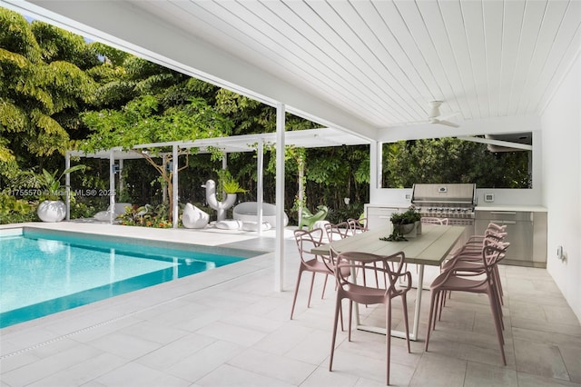 pool with outdoor dining area, a patio, area for grilling, ceiling fan, and exterior kitchen