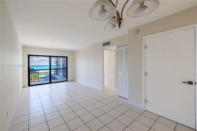 unfurnished room featuring light tile patterned floors, visible vents, and baseboards