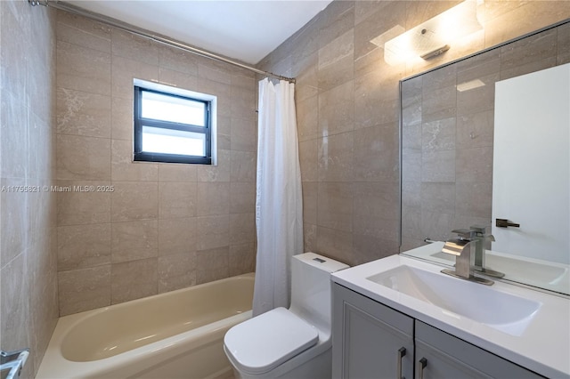 full bath featuring toilet, shower / bath combo with shower curtain, tile walls, and vanity