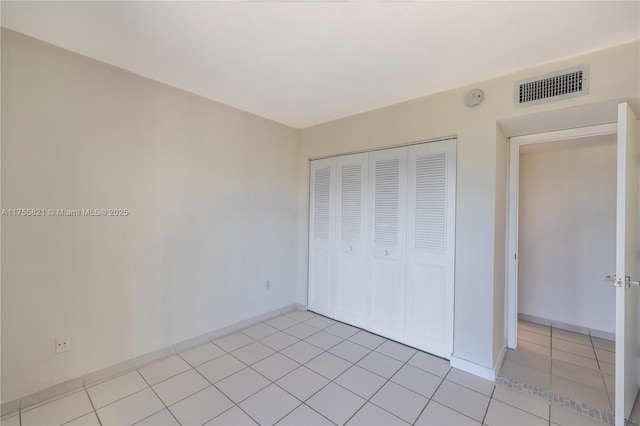 unfurnished bedroom with a closet, visible vents, baseboards, and light tile patterned flooring