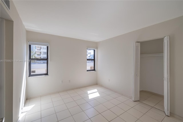 unfurnished bedroom with multiple windows, visible vents, a closet, and light tile patterned flooring