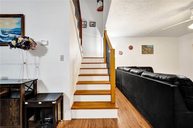 stairs featuring a textured ceiling and wood finished floors