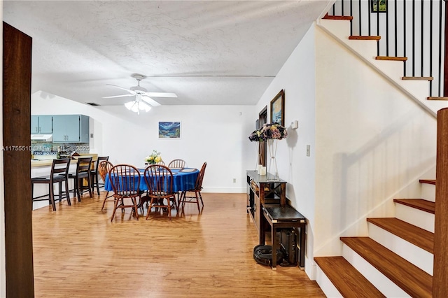 dining space featuring a textured ceiling, a ceiling fan, visible vents, stairway, and light wood finished floors