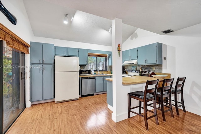 kitchen featuring light wood finished floors, stainless steel appliances, visible vents, blue cabinets, and under cabinet range hood