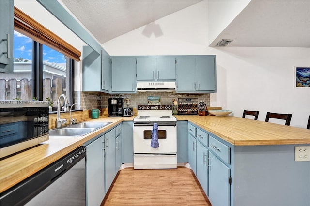 kitchen featuring a peninsula, a sink, vaulted ceiling, appliances with stainless steel finishes, and range hood