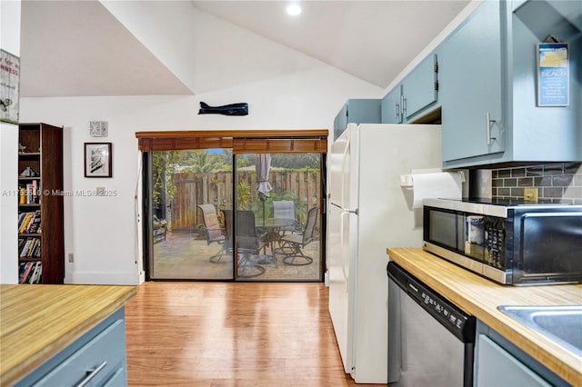 kitchen with vaulted ceiling, wooden counters, appliances with stainless steel finishes, blue cabinetry, and backsplash