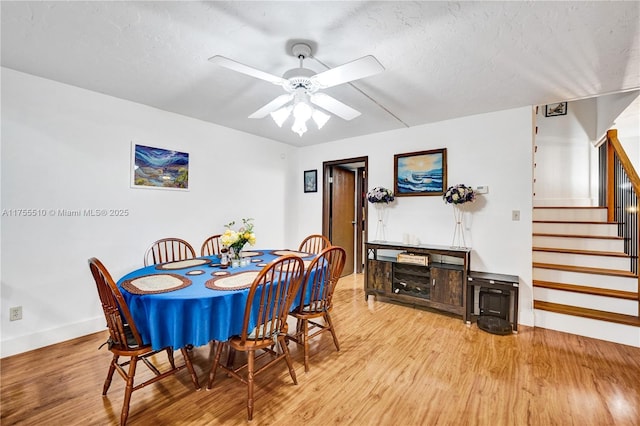 dining area with baseboards, ceiling fan, stairway, and wood finished floors