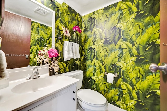 bathroom with toilet, wallpapered walls, visible vents, and vanity